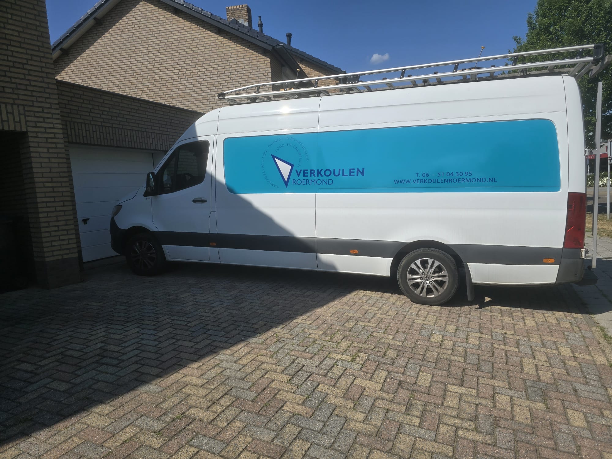 Bedrijfsbus van Verkoulen Roermond, zijaanzicht met dakwerken-belettering